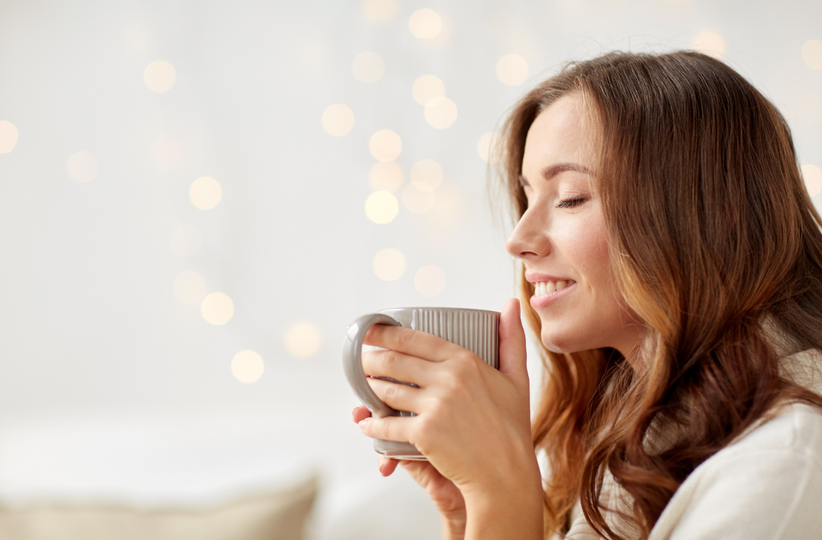 Woman enjoying a hot beverage in a white coffee mug